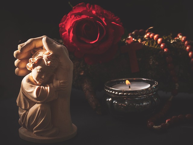 kind geborgen in einer hand mit Rose und Kerze